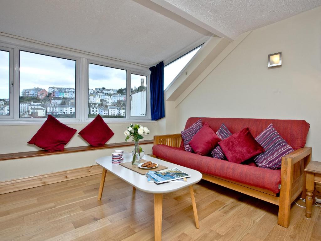 a living room with a red couch and some windows at Pilgrims Cottage in Brixham