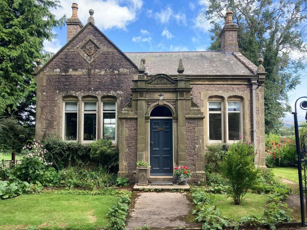 een oud bakstenen huis met een blauwe deur bij The Gatehouse Beckfoot Hall in Great Musgrave