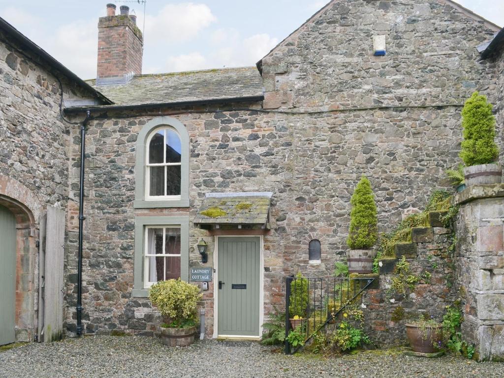 an old stone house with a green door at Laundry Cottage in Uldale
