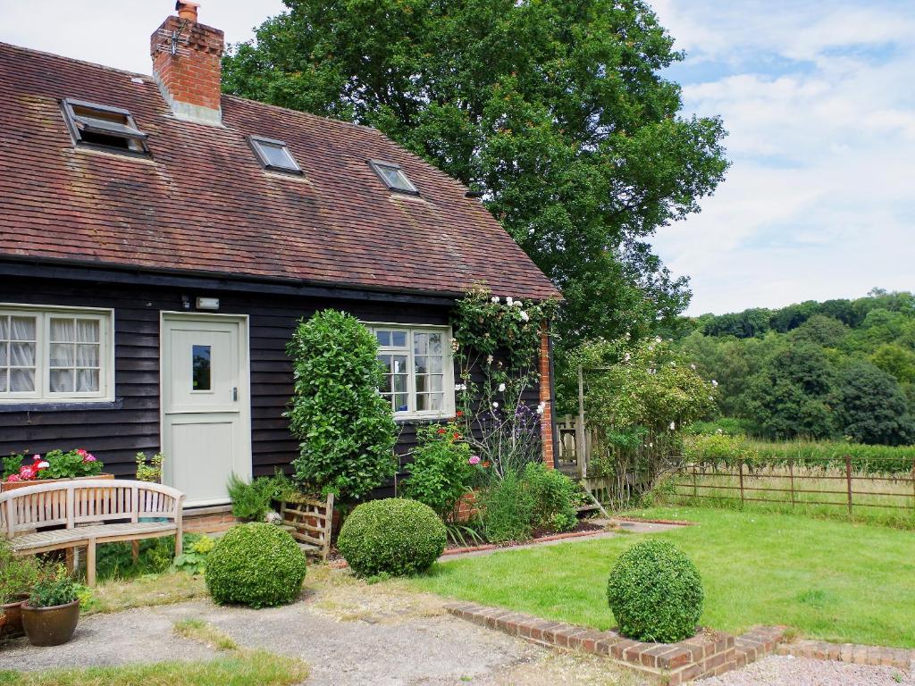 una pequeña casa con un banco en el patio en Malthouse Barn, en Hastingleigh