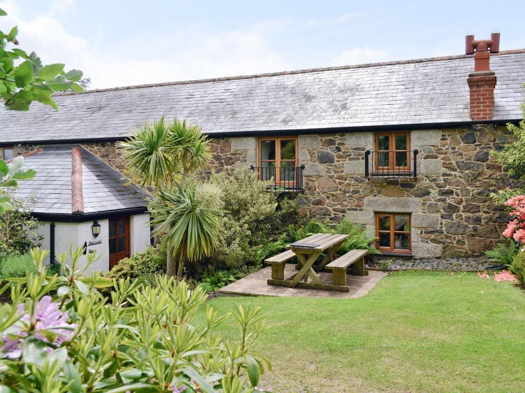 a stone cottage with a picnic table in the yard at Buzzard Barn in Saint Martins Green