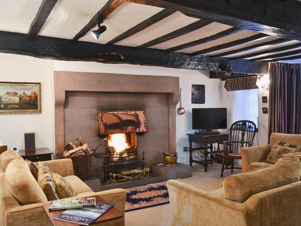 a living room with a fireplace and a tv at The Griffin in Broughton in Furness