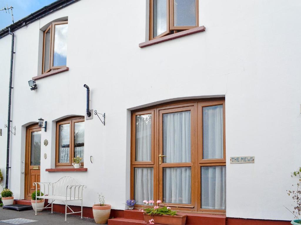 a white house with wooden windows at Draigs Cottage in Abergavenny