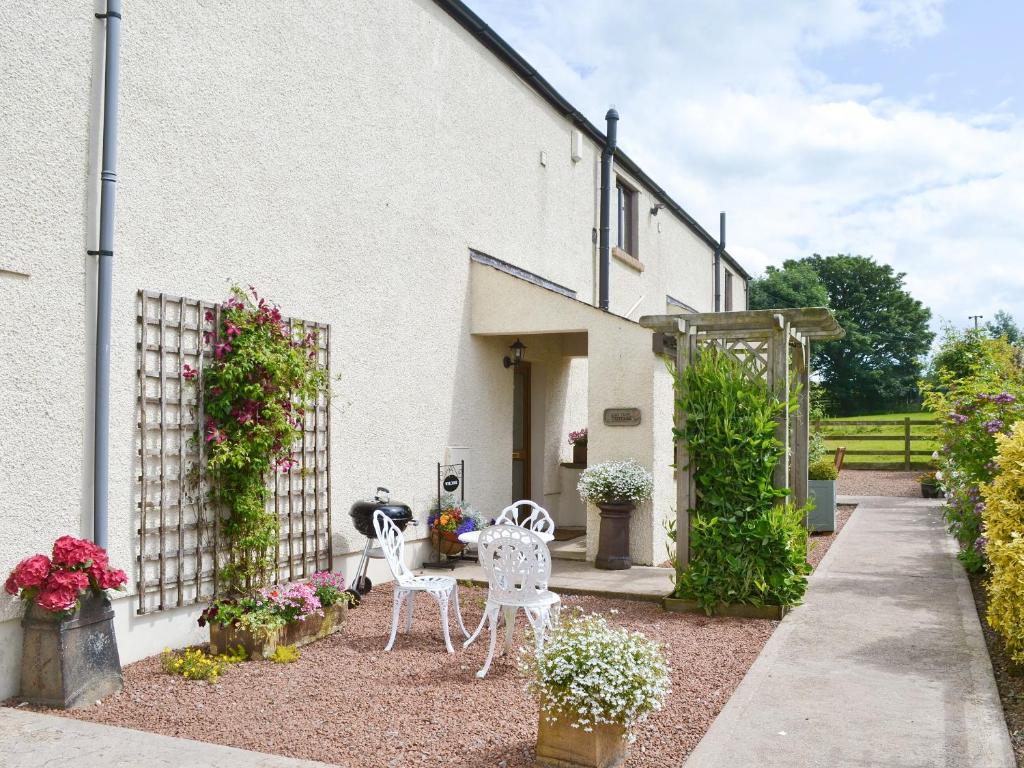 a garden with two chairs and a table in front of a building at Ash Tree Cottage in Bassenthwaite