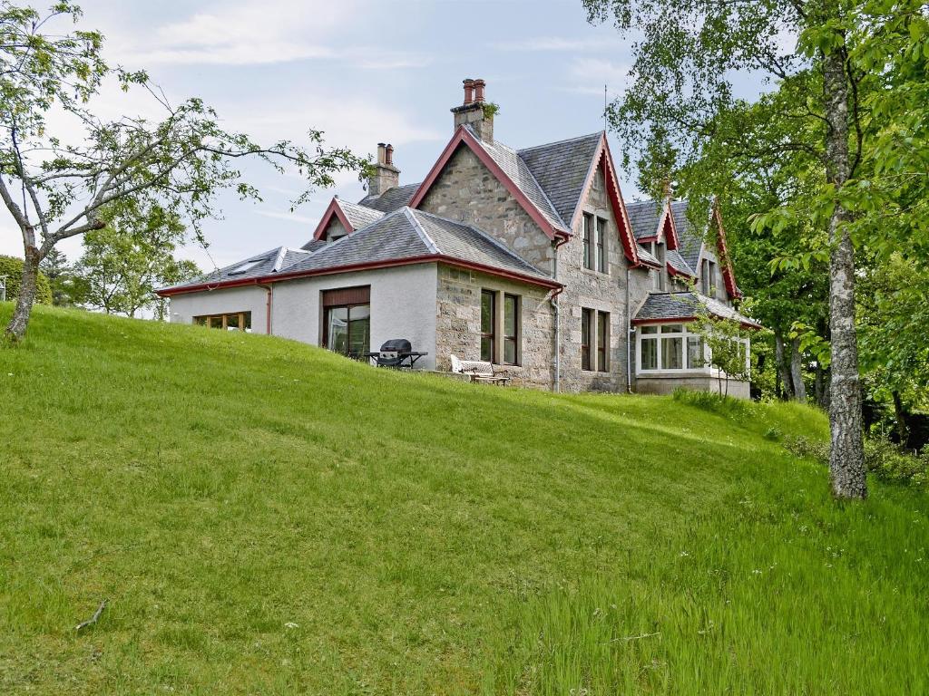 a house on top of a grassy hill at Treetops in Newtonmore