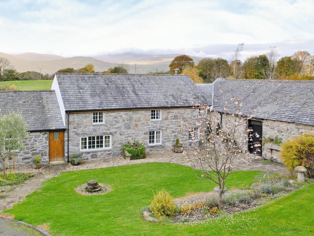 una antigua casa de piedra con un patio en Plas Iwrwg Granary - 28091 en Tal-y-Cafn