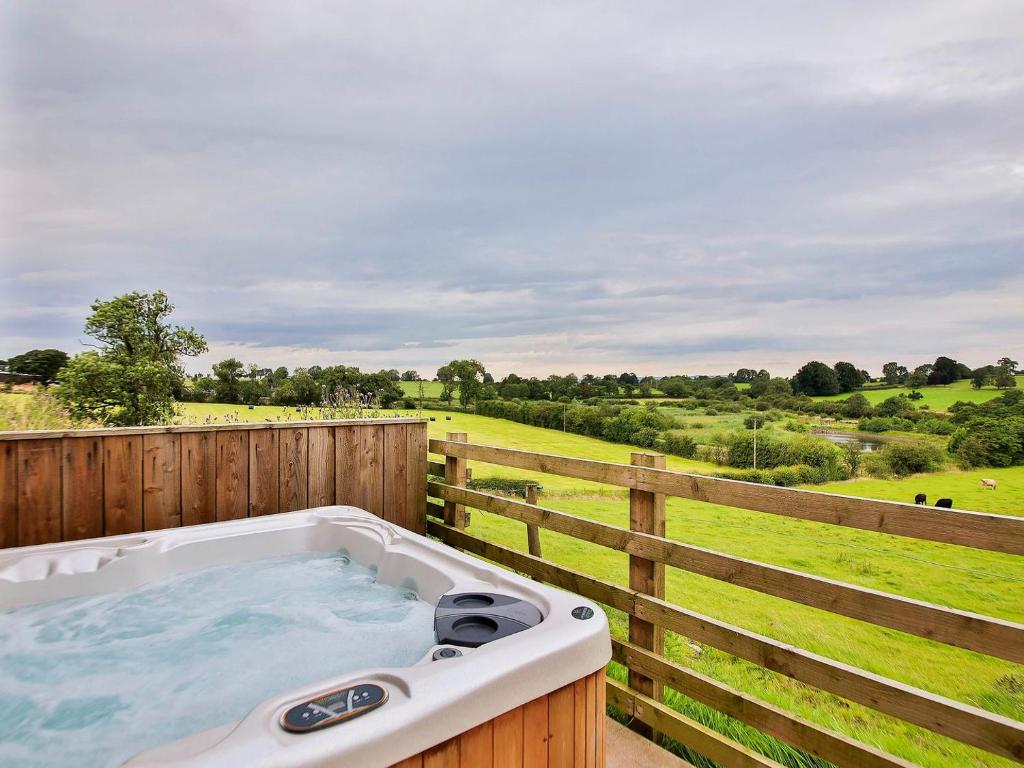 a hot tub on a fence with a view of a field at Horseshoe Cottage in Bolton by Bowland
