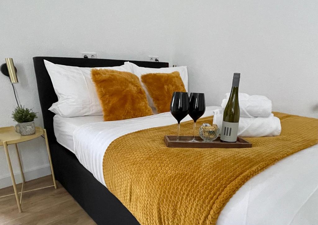 Bett mit einem Tablett mit zwei Gläsern und einer Flasche Wein in der Unterkunft moor-home Studio Apartment in Ganderkesee