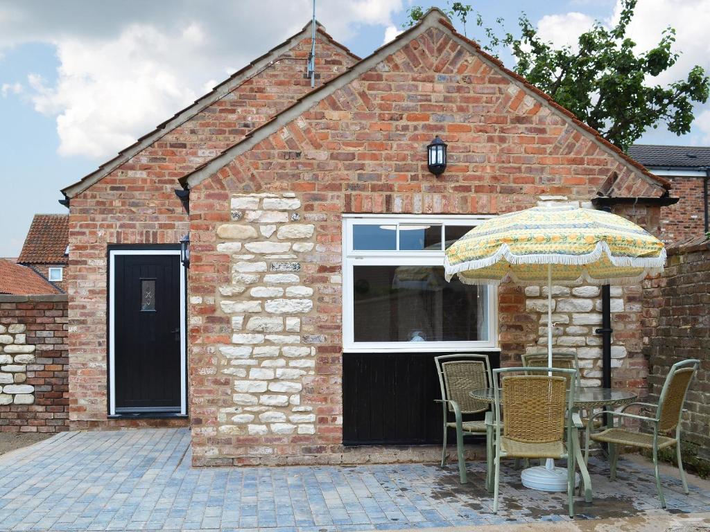 a brick house with a table and an umbrella at Freya Cottage in Flamborough