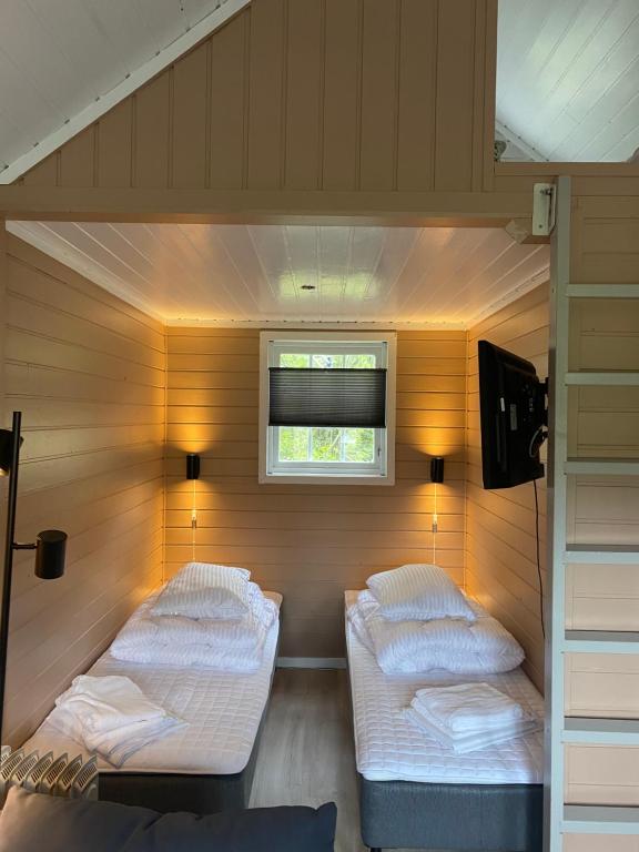 Duas camas num pequeno quarto com uma janela em Nygård Camping em Hjelle