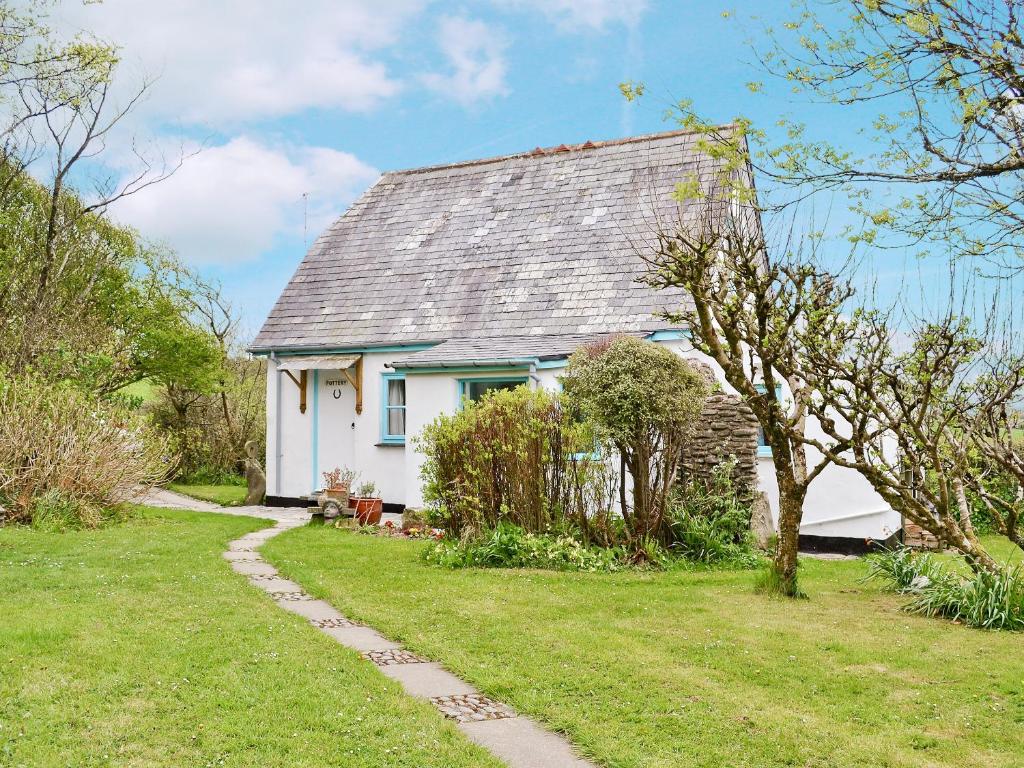 a white house with a gray roof in a yard at Pottery in Kilkhampton