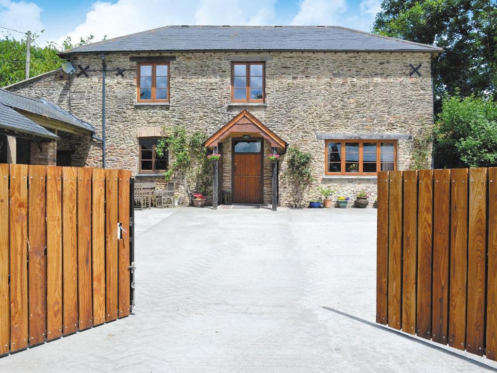 a brick house with a wooden gate and a driveway at The Coach House - Exg in Upton