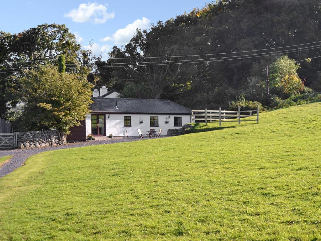 una casa blanca con un campo de hierba delante de ella en Tan Rallt Barn, en Tregarth