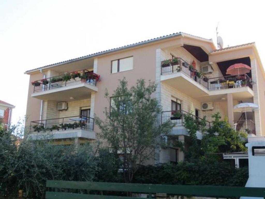 un gran edificio de apartamentos con balcones y sombrillas en Rooms Juran en Sukošan
