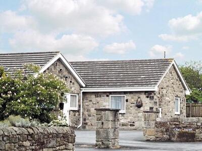 a stone house with a fence and a stone wall at Willow Cottage in Hadston