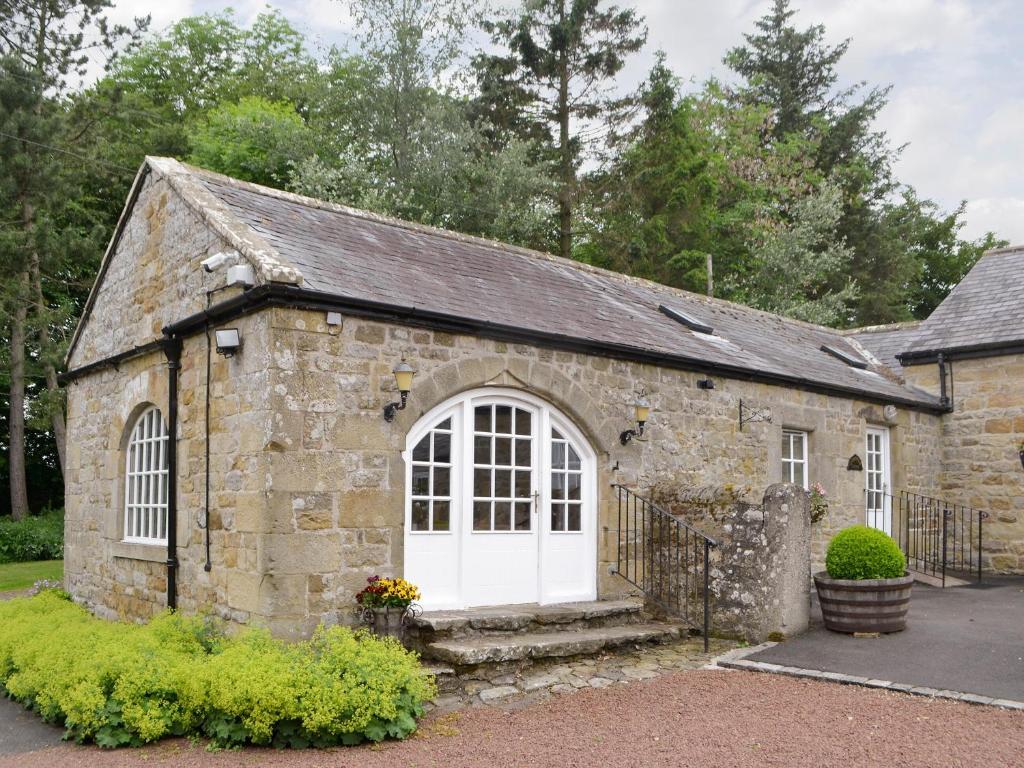 ElsdonにあるCobweb Cottageの白い扉のある古い石造りの建物