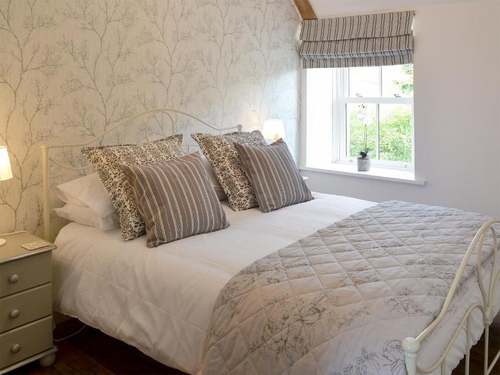 a bedroom with a white bed with pillows and a window at Melandra in Smeafield