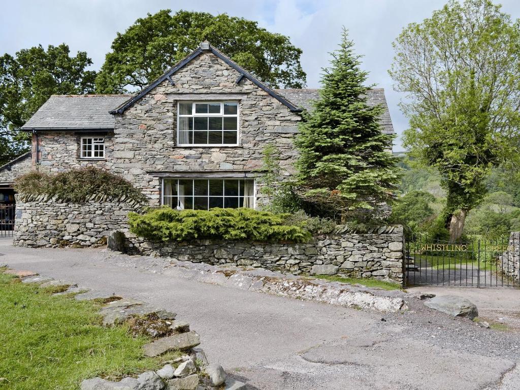 a stone house with a window and a stone wall at Whistling Green in Ulpha