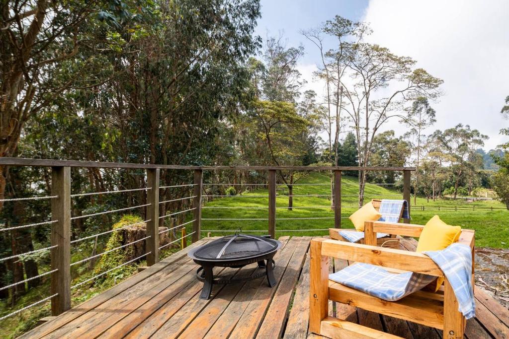 a deck with a fire pit and a bench and a grill at Cabaña de Hacienda Nebraska in Zipacón
