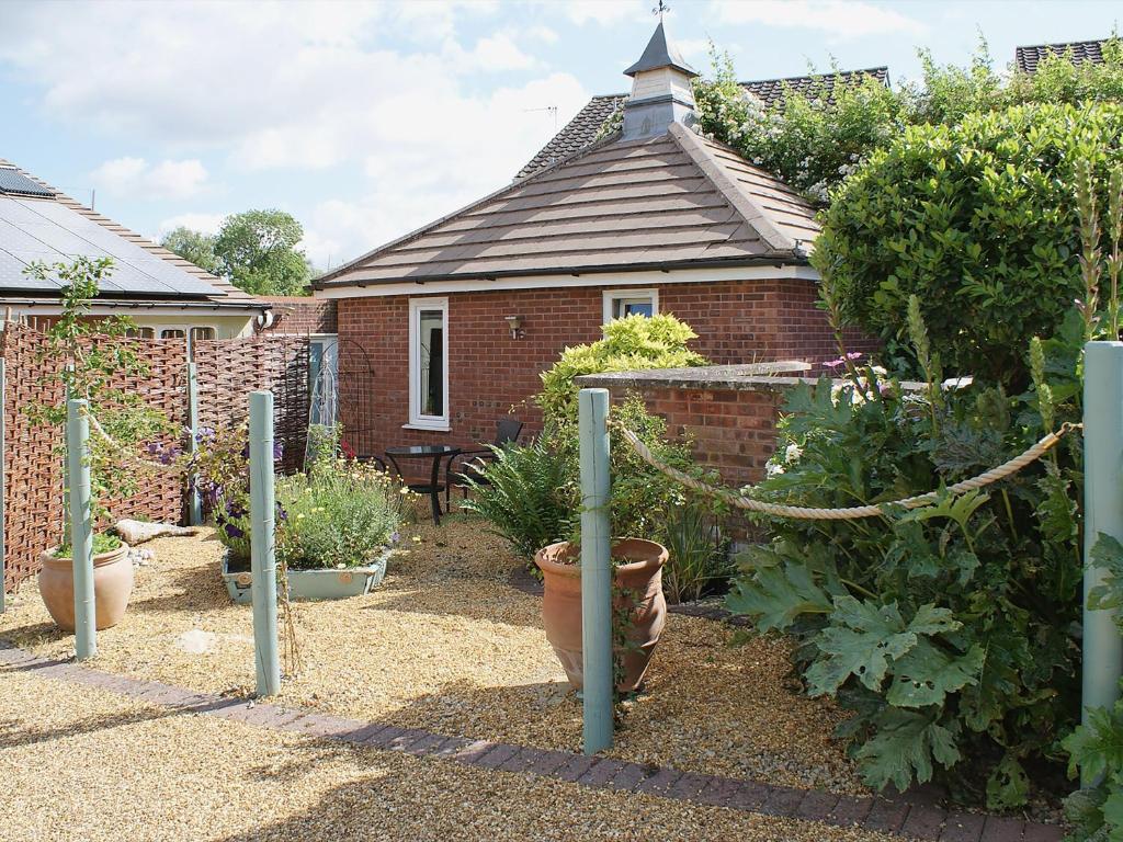 a garden with potted plants and a brick house at The Writing Room in Barford