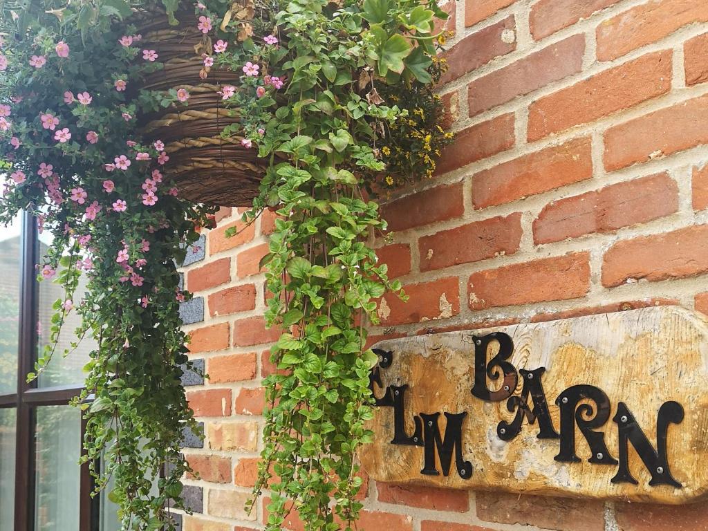 a hanging basket filled with flowers on a brick wall at Elm Barn View in Freethorpe