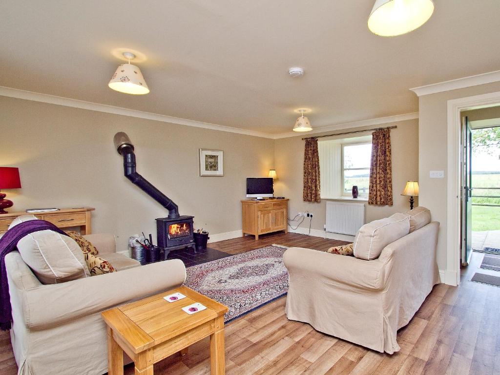 a living room with two chairs and a fireplace at The Hayloft - SNNL in Carnwath