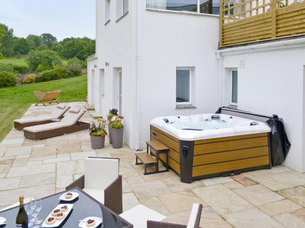 a backyard with a hot tub on a patio at Honey Pippin in Cheriton Bishop
