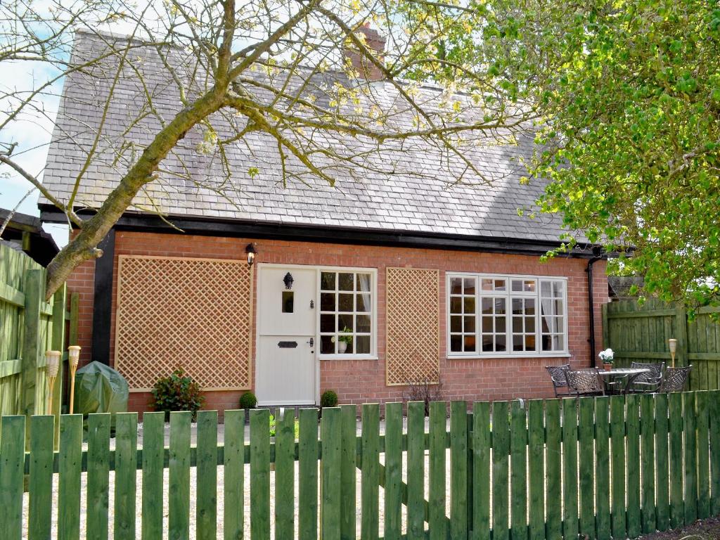 een rood bakstenen huis met een witte deur en een hek bij Tickton Hall Cottage in Tickton