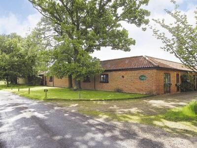 Boundary Gallery Cottage في فراملينغهام: منزل من الطوب مع شجرة بجوار شارع