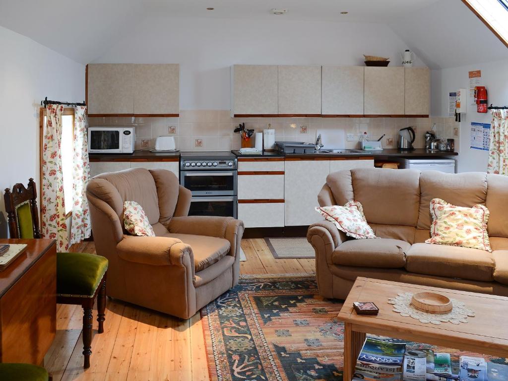 ジョン・オ・グローツにあるStable Cottageのリビングルーム(ソファ2台付)、キッチンが備わります。