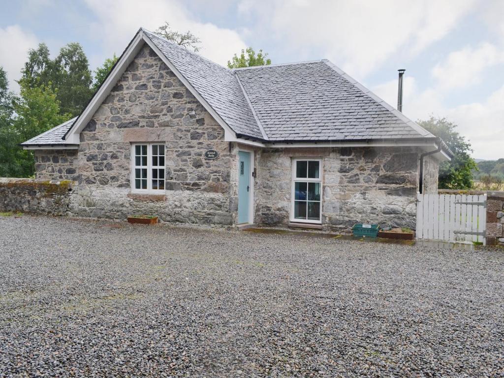 a stone house with a gravel driveway in front of it at The Kennels Bothy - Beaufort Estate in Belladrum