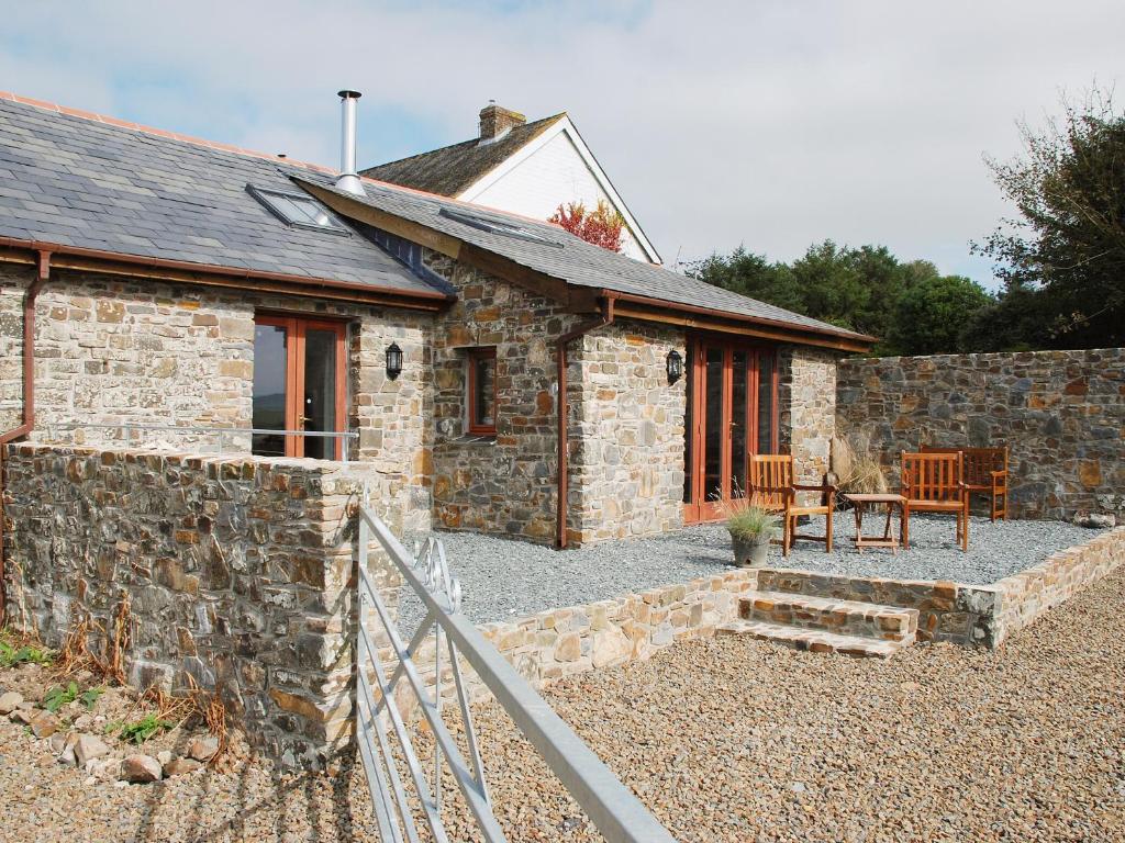 a stone house with a stone wall and a patio at The Cart House in Milford