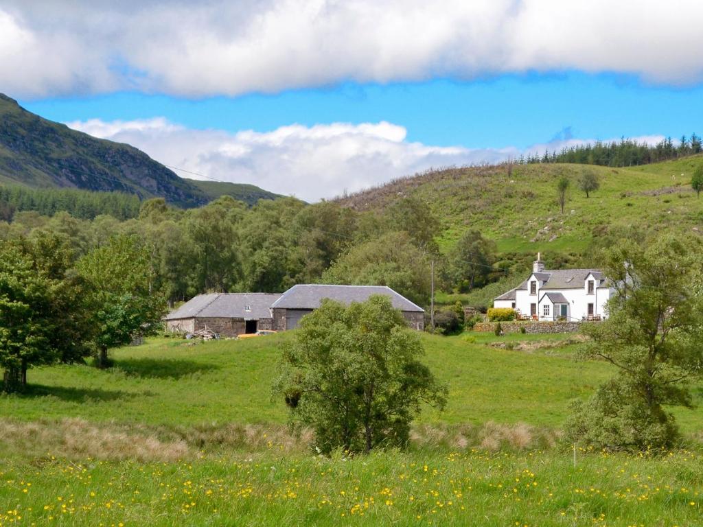 a white house in a green field with mountains at Dalvanie Mill - S4241 in Tulchan