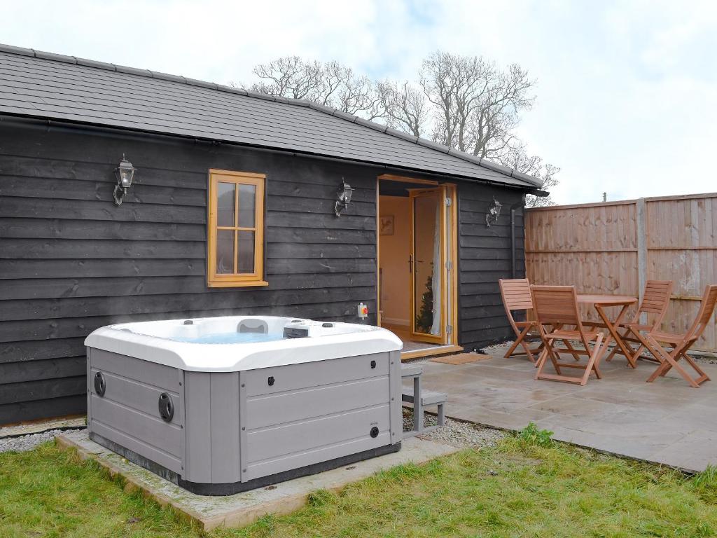 a hot tub in a yard next to a house at Dairy Cottage in Alkham