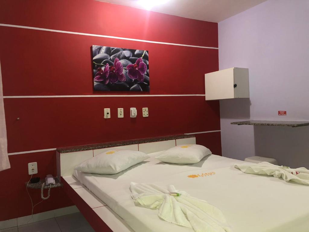 2 camas en una habitación con una pared roja en Hotel Lotus, en Salvador