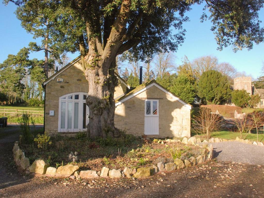 a small house with a tree in front of it at The Byre in West Stour