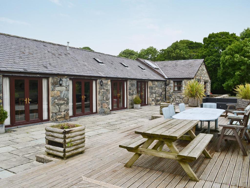a patio with a picnic table and a stone building at Glanrafon Isaf in Llanwnda