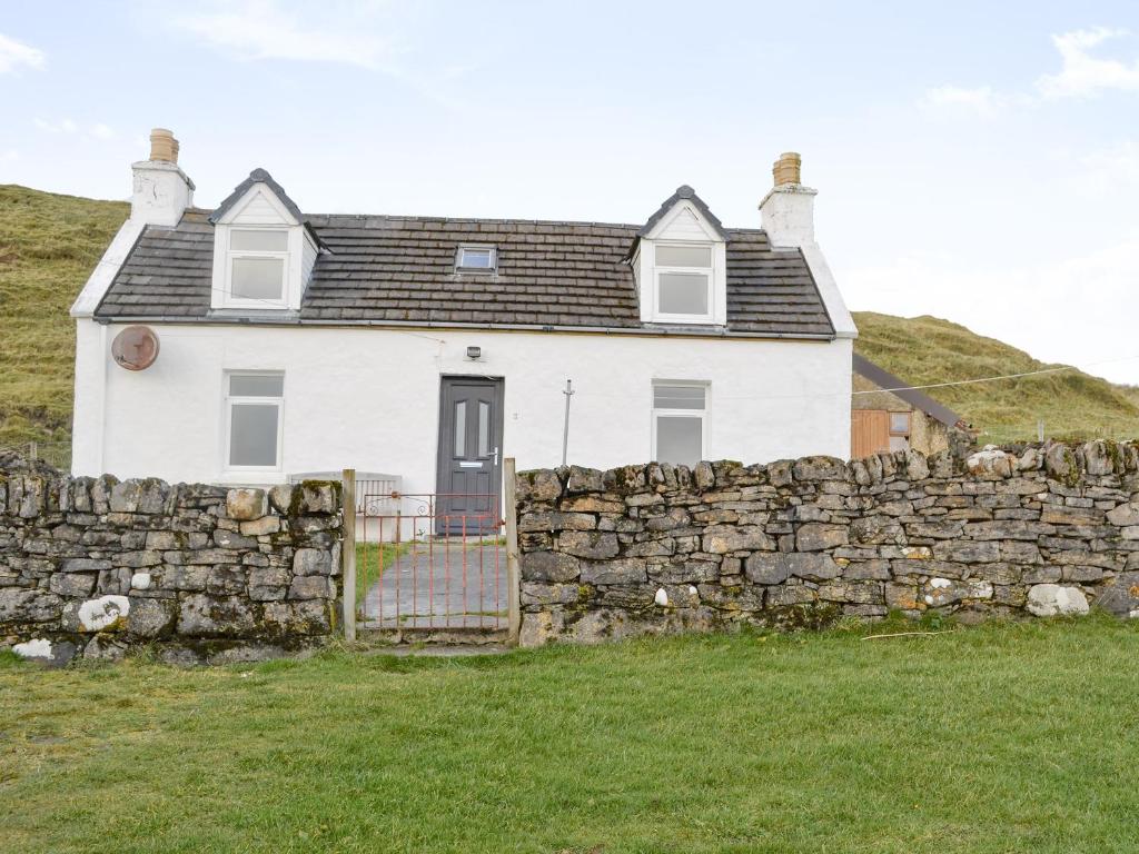 a white house behind a stone wall at 3 Breckery in Staffin
