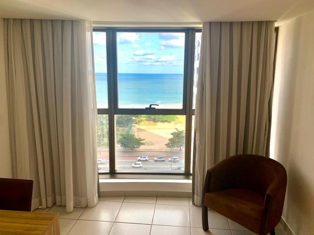 Cette chambre dispose d'une grande fenêtre avec une chaise et offre une vue sur l'océan. dans l'établissement Beach Class Executive, à Récife