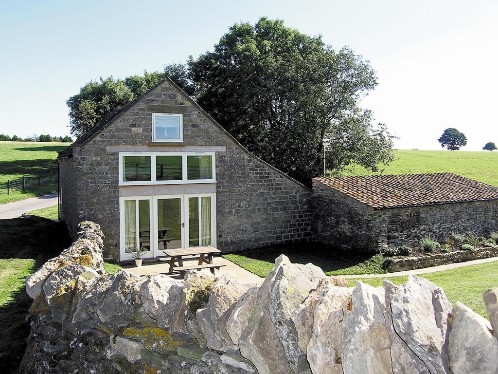a small stone house with a stone wall at Pasture Barn in Lockton
