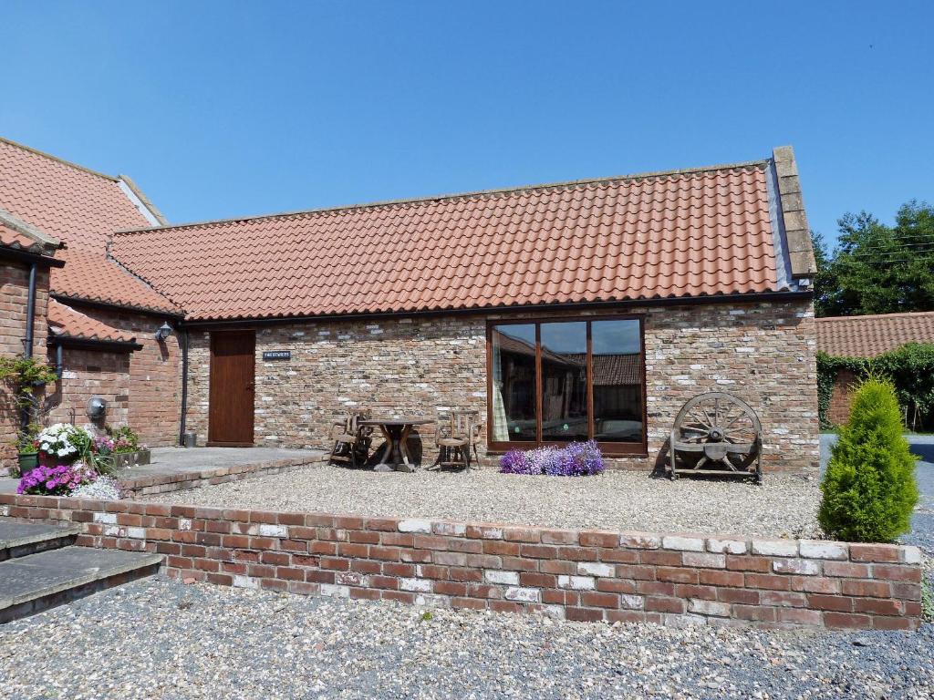 a brick house with a brick wall and a patio at The Stables in Hornsea