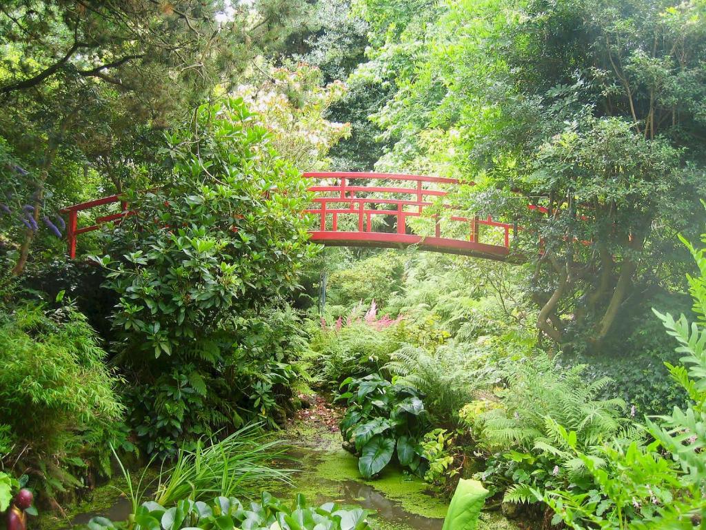 un puente rojo en medio de un jardín en Cowbeech Farm Cottage en Herstmonceux