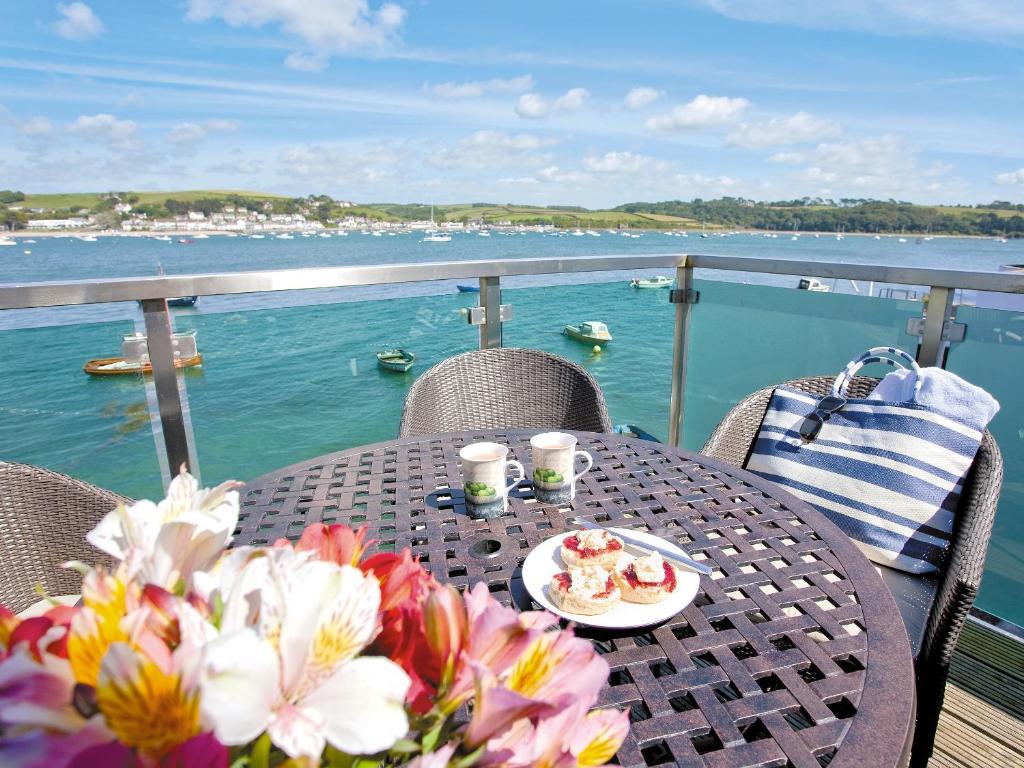 a table with a plate of food and flowers on a balcony at Shorewaters in Appledore