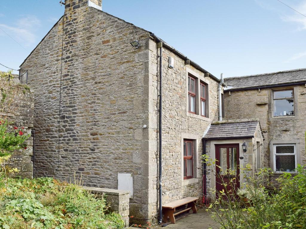 an old brick building with a bench in front of it at Sycamore Cottage in Grassington