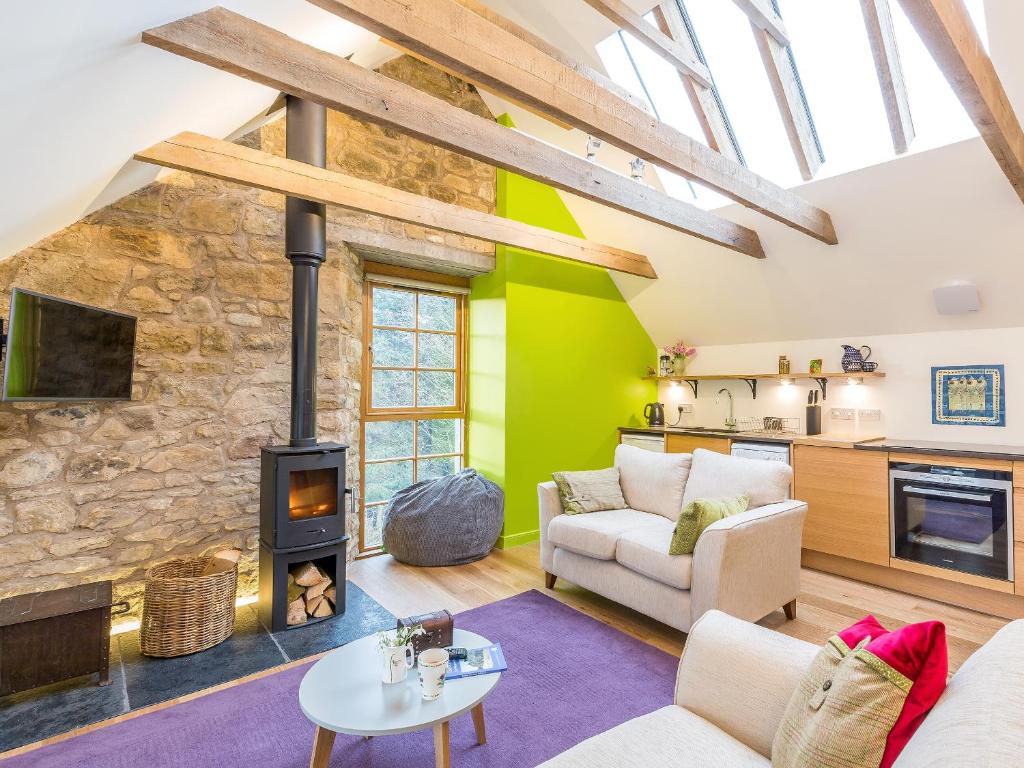 a living room with a stone wall and a wood stove at The Hayloft in Blitterlees