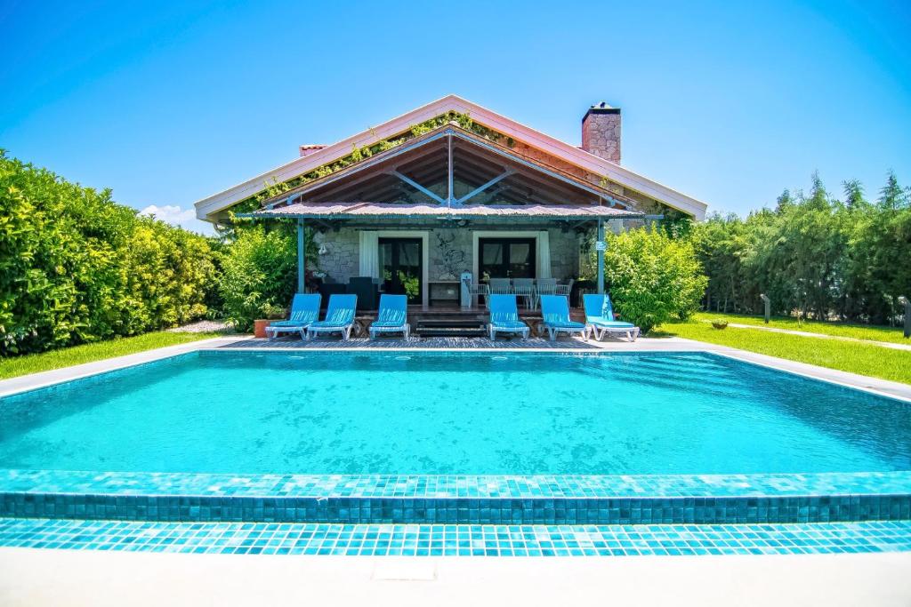 a swimming pool with blue chairs and a house at Dalyan Villa StoneHouse-1 in Dalyan