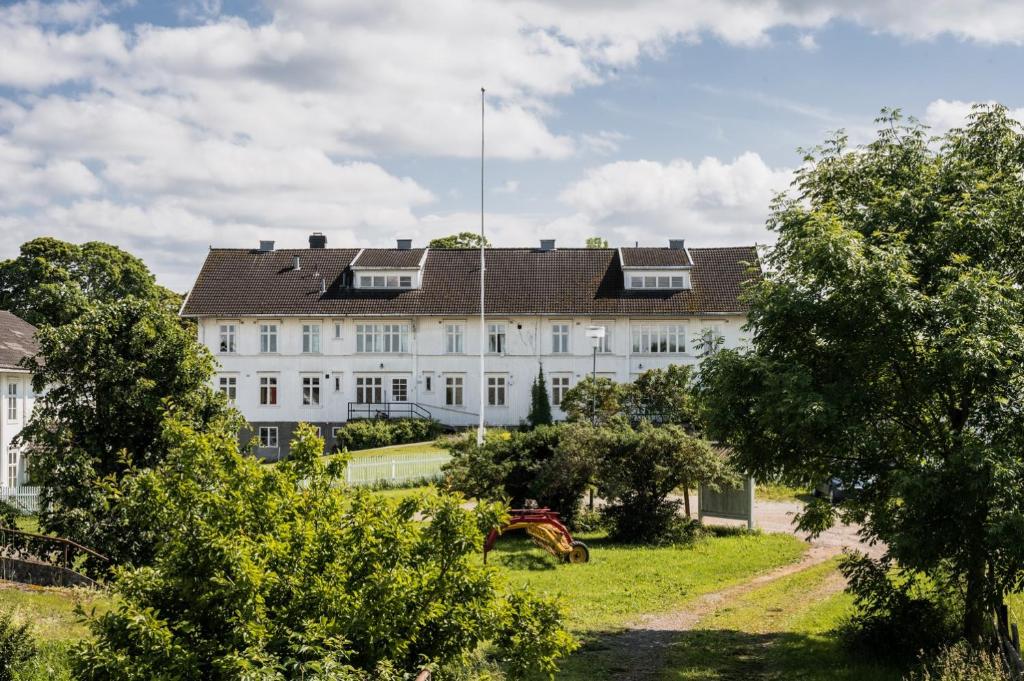 a large white building with a brown roof at Fokhol Gård Gjestehus in Stange