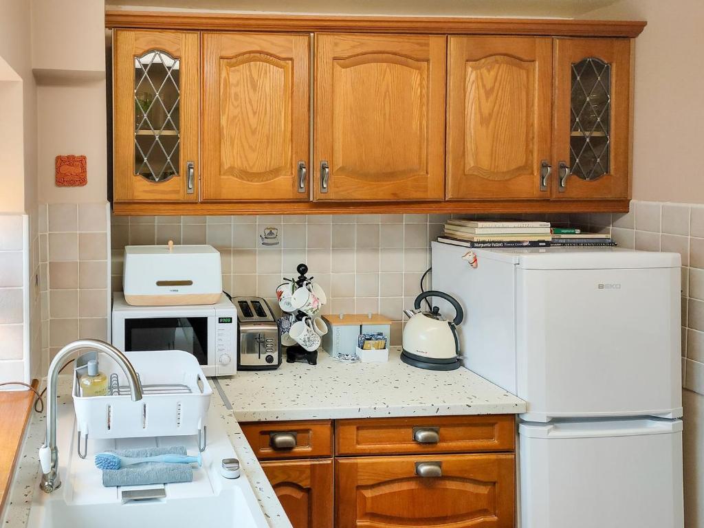a kitchen with a sink and a white refrigerator at Cow Cottage in Churchill