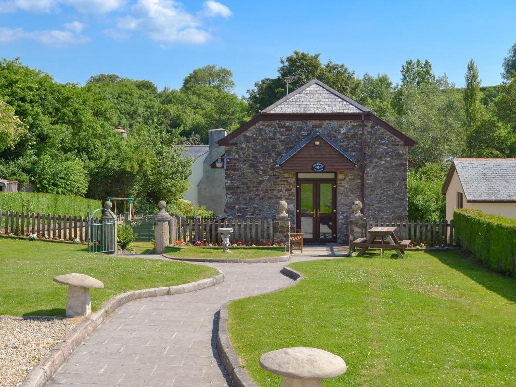 un jardín con un edificio de piedra con una mesa y setas en Rose Bank Cottage - W4218, en Lewdown