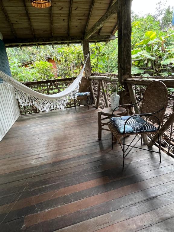 a porch with a hammock and chairs on it at Casa do Rio in Caraíva